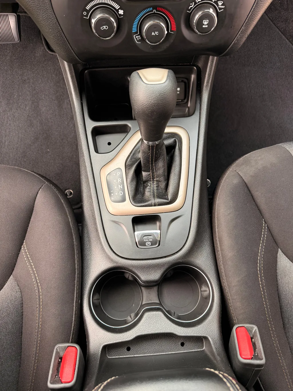 Center console of the silver Jeep Cherokee after an interior detail, cup holders and shifter surround wiped clean
