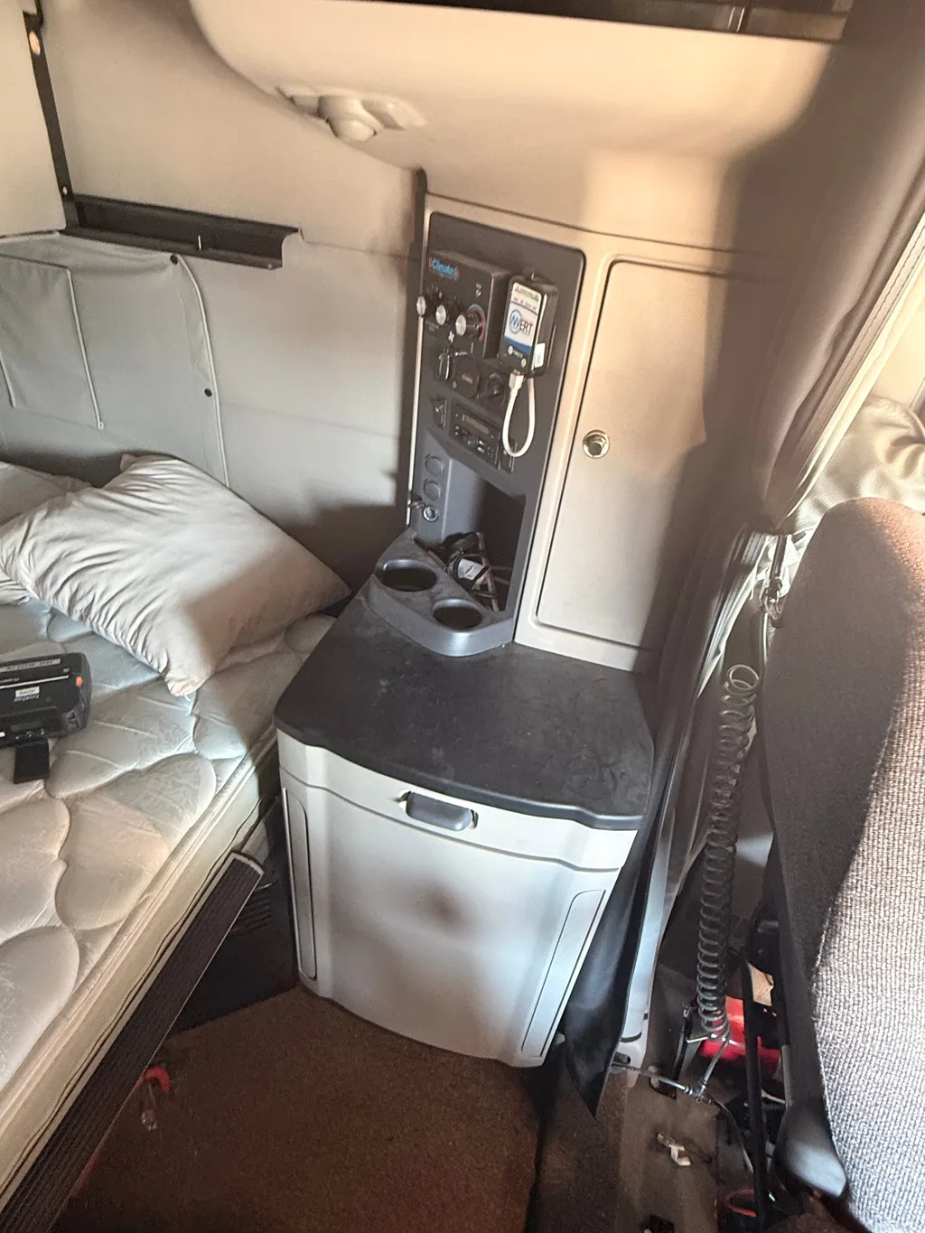 Sleeper cabinet and refrigerator in a semi truck before detailing, dust and smudges on the black counter top and fridge door