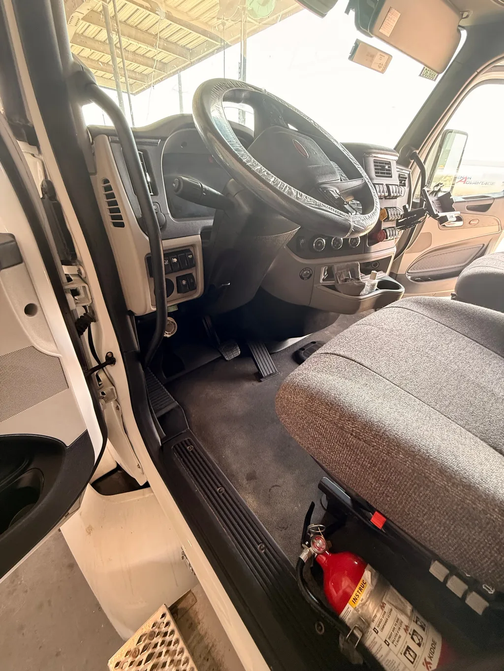 Cab of the semi truck with a sleeper after an interior detail, floor clean and the steering wheel wrapped in plastic