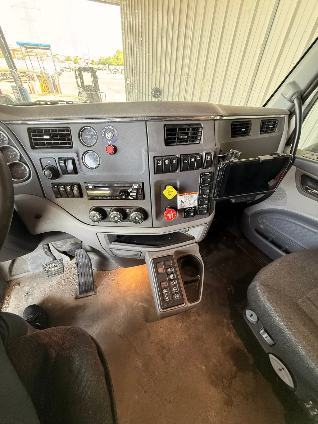 Dash and center floor of a semi truck cab before detailing, floor brown with dirt under the gear selector