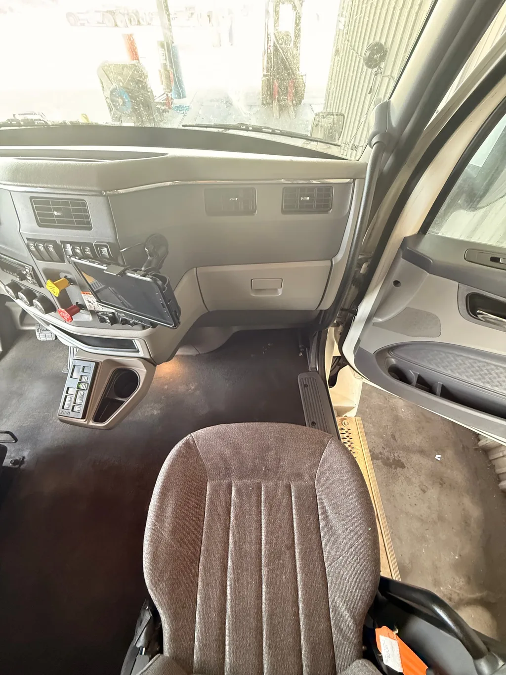 Passenger side of the semi truck cab after an interior detail, floor clean and dash wiped down, with the door open